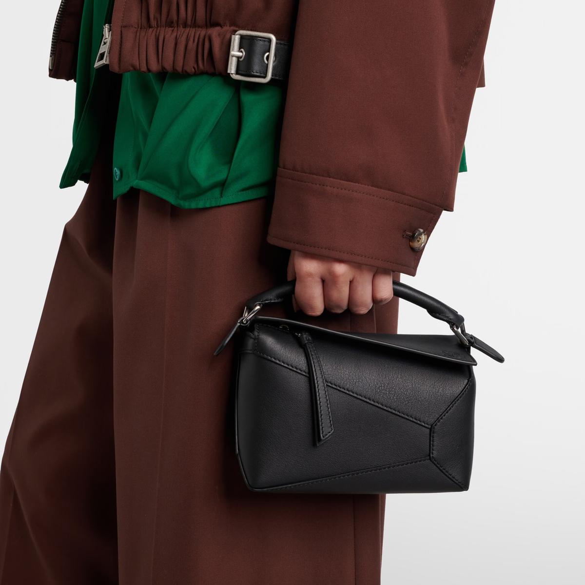 Loewe Puzzle Edge Mini in black calfskin, carried by hand with a brown coat