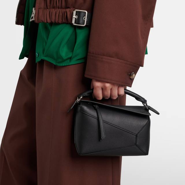 Loewe Puzzle Edge Mini in black calfskin, carried by hand with a brown coat