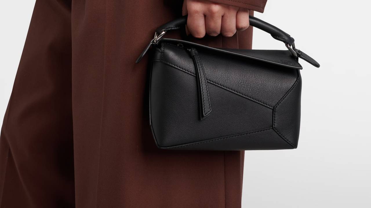 Loewe Puzzle Edge Mini in black calfskin, carried by hand with a brown coat